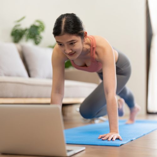Young woman Exercising At Laptop Having Online Training At Home.